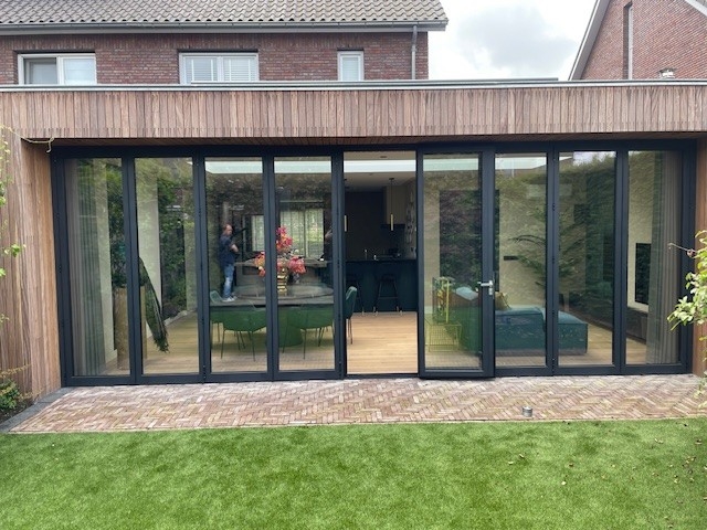 Black aluminum bifold glass doors fully opened connecting indoor living space to outdoor patio area
