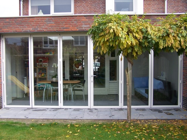 Black aluminum bifold glass doors fully opened connecting indoor living space to outdoor patio area
