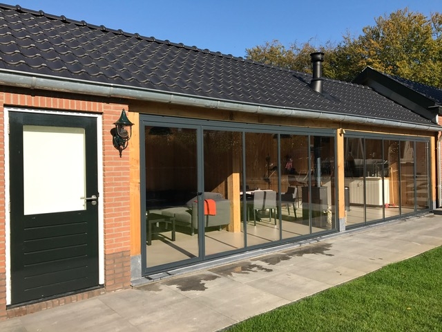 Black aluminum bifold glass doors fully opened connecting indoor living space to outdoor patio area