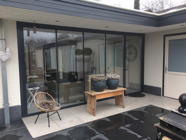 Black aluminum bifold glass doors fully opened connecting indoor living space to outdoor patio area