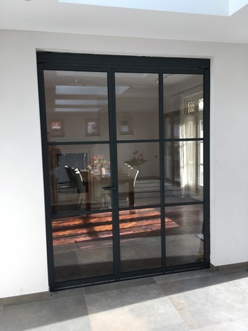 Black aluminum bifold glass doors fully opened connecting indoor living space to outdoor patio area