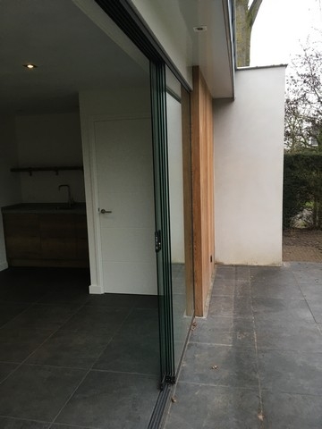Black aluminum bifold glass doors fully opened connecting indoor living space to outdoor patio area