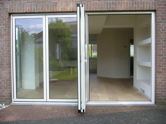 Black aluminum bifold glass doors fully opened connecting indoor living space to outdoor patio area