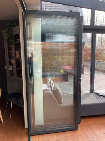 Black aluminum bifold glass doors fully opened connecting indoor living space to outdoor patio area