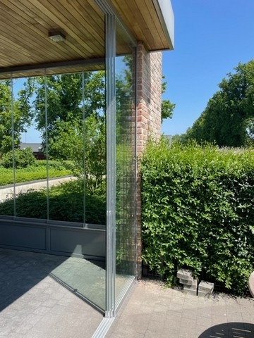 Black aluminum bifold glass doors fully opened connecting indoor living space to outdoor patio area