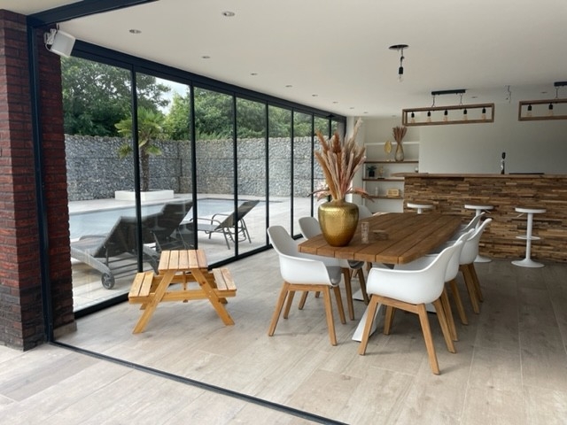 Black aluminum bifold glass doors fully opened connecting indoor living space to outdoor patio area
