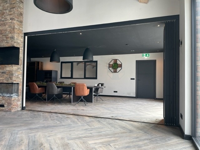 Black aluminum bifold glass doors fully opened connecting indoor living space to outdoor patio area