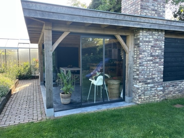 Black aluminum bifold glass doors fully opened connecting indoor living space to outdoor patio area