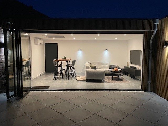 Black aluminum bifold glass doors fully opened connecting indoor living space to outdoor patio area
