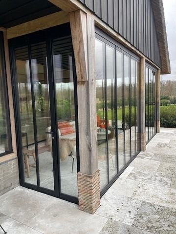 Black aluminum bifold glass doors fully opened connecting indoor living space to outdoor patio area
