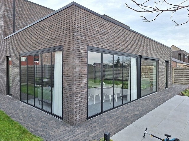 Black aluminum bifold glass doors fully opened connecting indoor living space to outdoor patio area