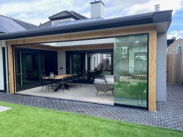 Black aluminum bifold glass doors fully opened connecting indoor living space to outdoor patio area