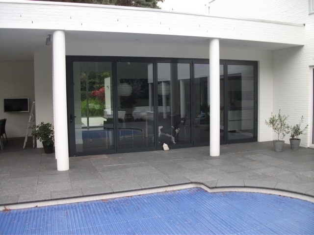 Black aluminum bifold glass doors fully opened connecting indoor living space to outdoor patio area