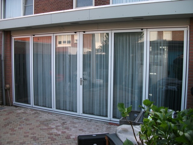 Black aluminum bifold glass doors fully opened connecting indoor living space to outdoor patio area