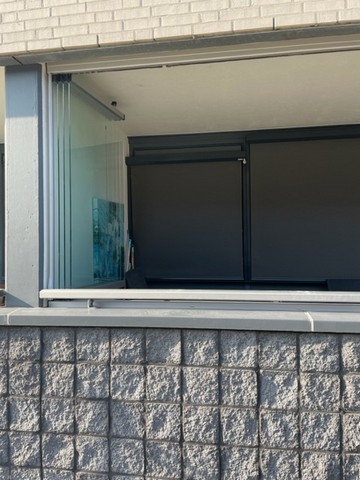 Black aluminum bifold glass doors fully opened connecting indoor living space to outdoor patio area