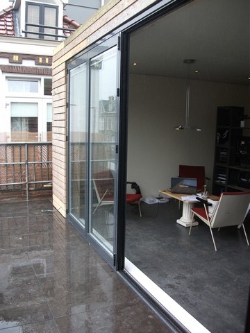 Black aluminum bifold glass doors fully opened connecting indoor living space to outdoor patio area