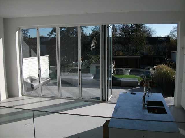 Black aluminum bifold glass doors fully opened connecting indoor living space to outdoor patio area