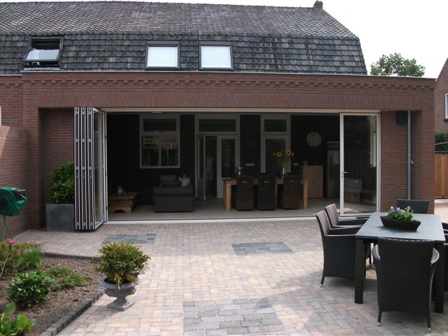 Black aluminum bifold glass doors fully opened connecting indoor living space to outdoor patio area
