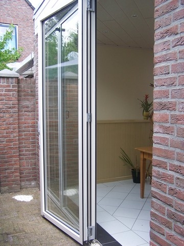 Black aluminum bifold glass doors fully opened connecting indoor living space to outdoor patio area