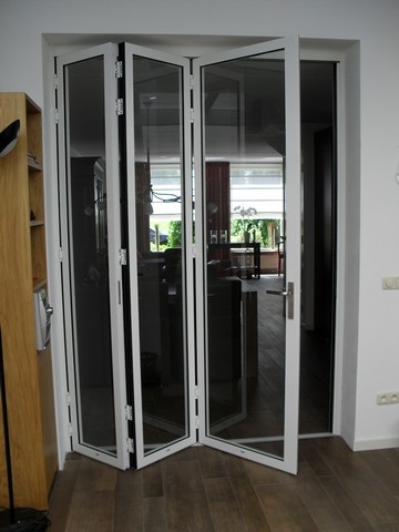 Black aluminum bifold glass doors fully opened connecting indoor living space to outdoor patio area