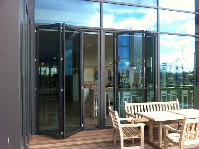 Black aluminum bifold glass doors fully opened connecting indoor living space to outdoor patio area