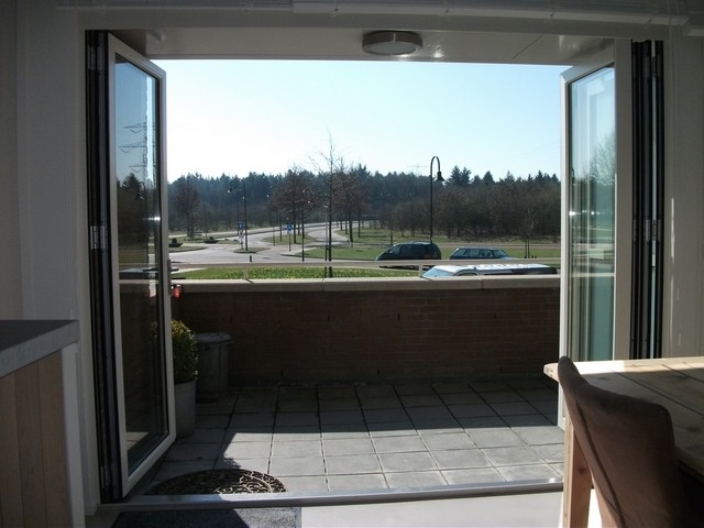 Black aluminum bifold glass doors fully opened connecting indoor living space to outdoor patio area