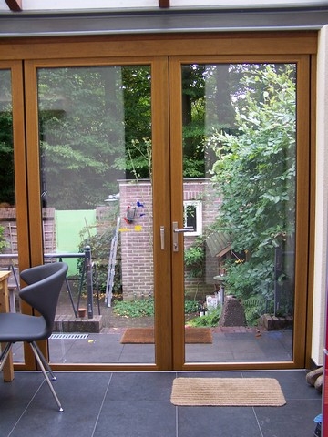 Black aluminum bifold glass doors fully opened connecting indoor living space to outdoor patio area