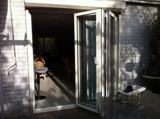 Black aluminum bifold glass doors fully opened connecting indoor living space to outdoor patio area