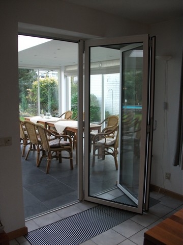 Black aluminum bifold glass doors fully opened connecting indoor living space to outdoor patio area