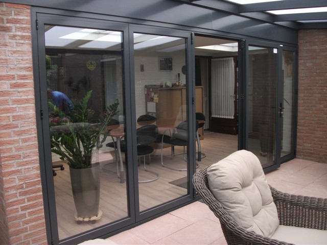 Black aluminum bifold glass doors fully opened connecting indoor living space to outdoor patio area