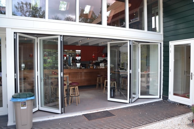 Black aluminum bifold glass doors fully opened connecting indoor living space to outdoor patio area