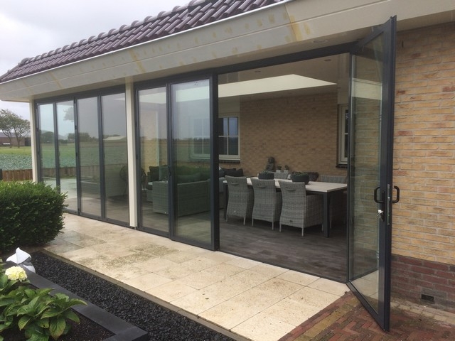 Black aluminum bifold glass doors fully opened connecting indoor living space to outdoor patio area