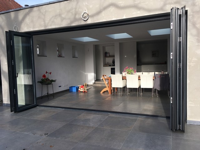 Black aluminum bifold glass doors fully opened connecting indoor living space to outdoor patio area