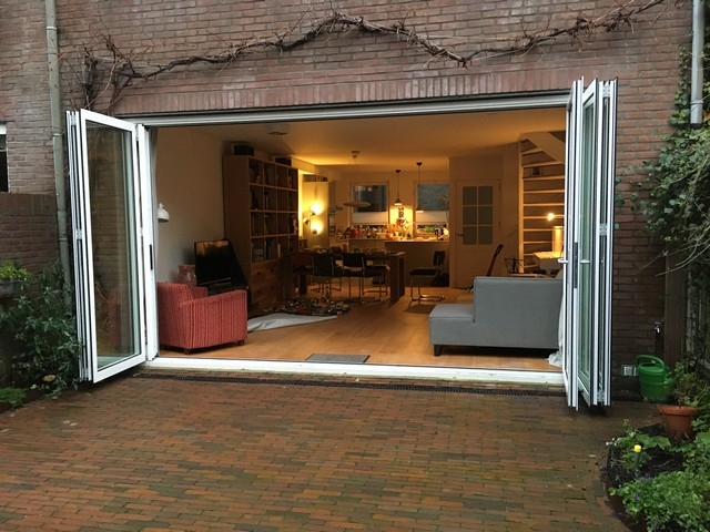 Black aluminum bifold glass doors fully opened connecting indoor living space to outdoor patio area