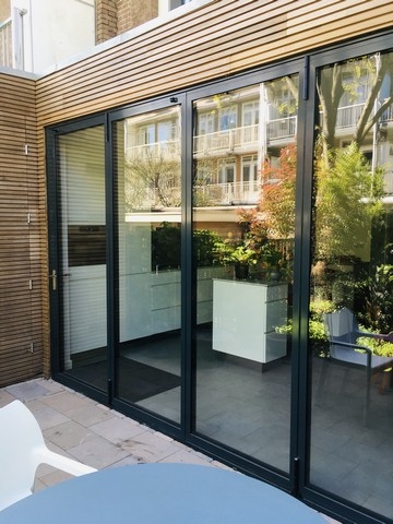 Black aluminum bifold glass doors fully opened connecting indoor living space to outdoor patio area