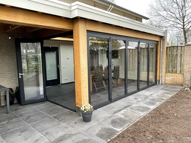 Black aluminum bifold glass doors fully opened connecting indoor living space to outdoor patio area
