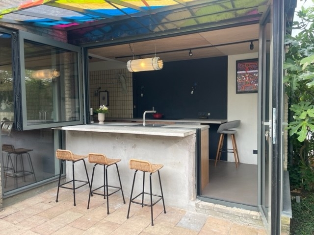 Black aluminum bifold glass doors fully opened connecting indoor living space to outdoor patio area