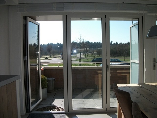 Black aluminum bifold glass doors fully opened connecting indoor living space to outdoor patio area