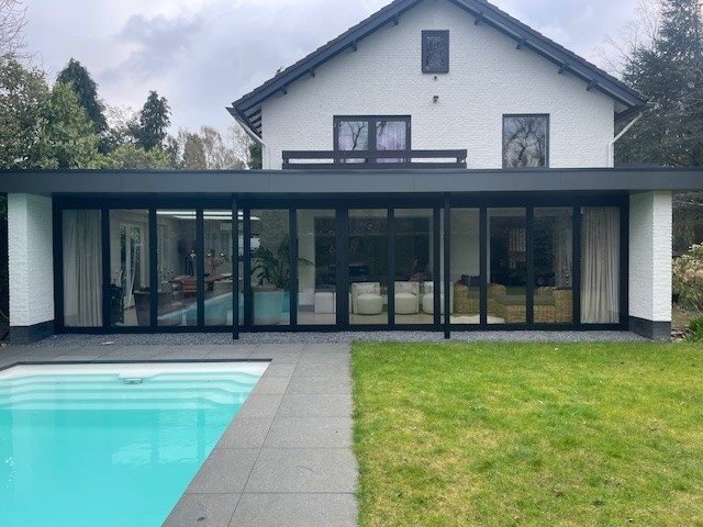 Black aluminum bifold glass doors fully opened connecting indoor living space to outdoor patio area