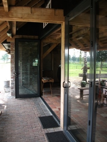 Black aluminum bifold glass doors fully opened connecting indoor living space to outdoor patio area