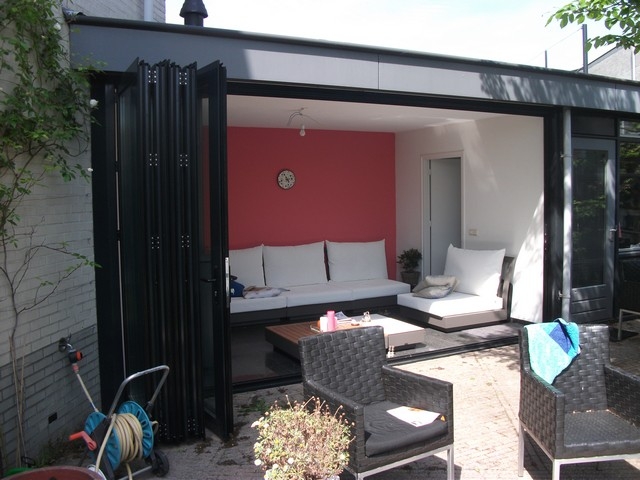 Black aluminum bifold glass doors fully opened connecting indoor living space to outdoor patio area