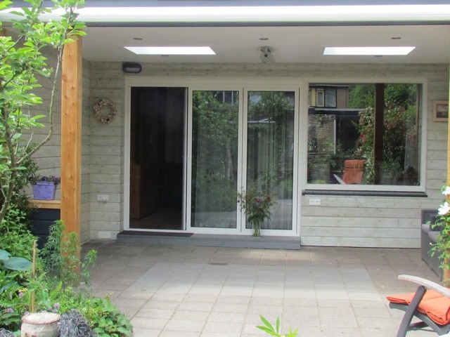 Black aluminum bifold glass doors fully opened connecting indoor living space to outdoor patio area