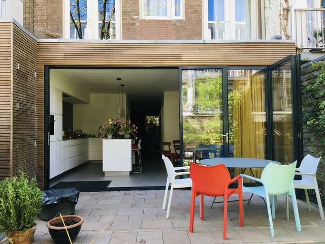 Black aluminum bifold glass doors fully opened connecting indoor living space to outdoor patio area