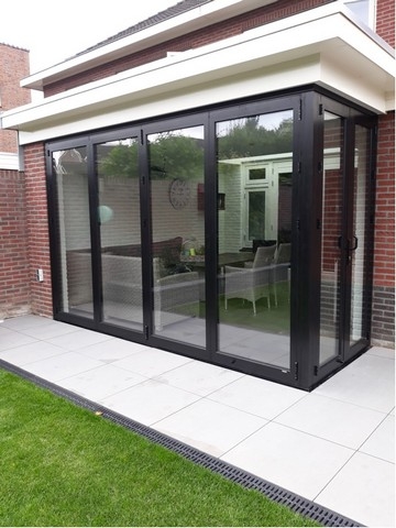 Black aluminum bifold glass doors fully opened connecting indoor living space to outdoor patio area