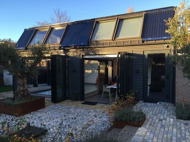 Black aluminum bifold glass doors fully opened connecting indoor living space to outdoor patio area