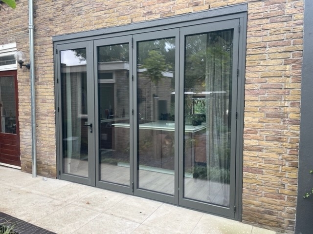 Black aluminum bifold glass doors fully opened connecting indoor living space to outdoor patio area
