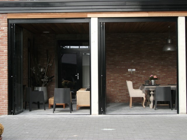Black aluminum bifold glass doors fully opened connecting indoor living space to outdoor patio area