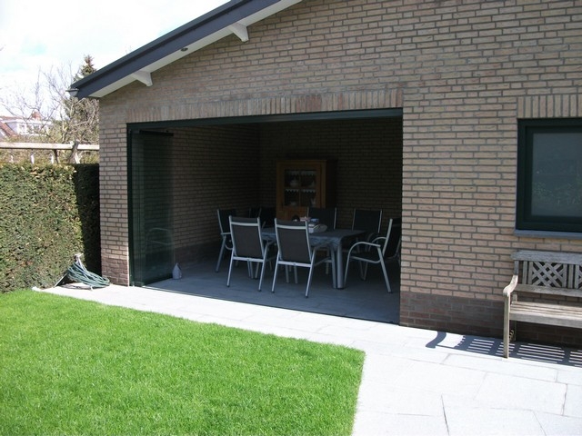 Black aluminum bifold glass doors fully opened connecting indoor living space to outdoor patio area