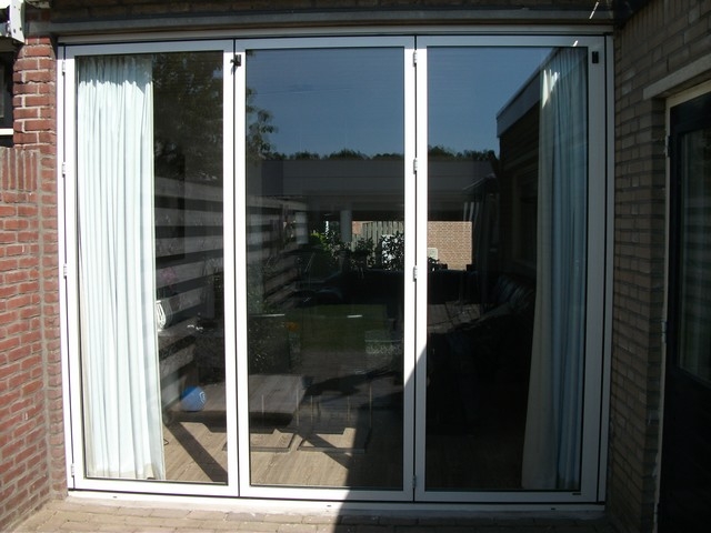Black aluminum bifold glass doors fully opened connecting indoor living space to outdoor patio area