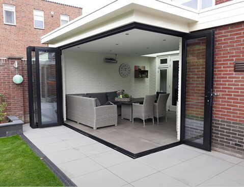 Black aluminum bifold glass doors fully opened connecting indoor living space to outdoor patio area